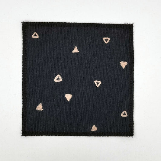 a square patch made out of black canvas, handstitched with scattered peach triangles, some as outlines some with a line fill, with overlocked edges, on a white background