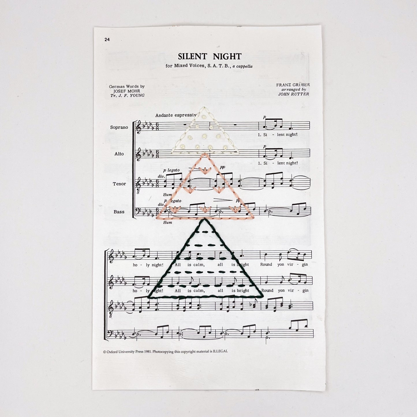 Christmas sheet music for the song Silent Night, hand stitched on with a Christmas tree made from triangles filled with different types of stitches, in green, peach and ivory thread